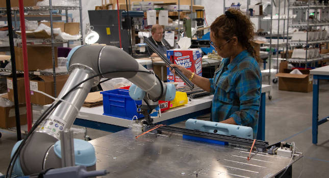 Collaborative robot working alongside a human in a manufacturing facility